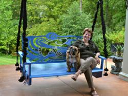 Becky Irvine, and Dozzer, relax on "Don't Be Koi,"one of her new metal Weather...Or Not™ swings, which has a patent pending on its unique design. The swing back can be tilted back and forth or be lifted out so the bench can be used as a bed.